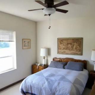A cozy bedroom with a bed, lamps, and artwork on the walls.
