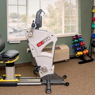 A therapy room with exercise equipment and a rack of colorful weights.