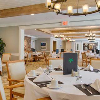 An elegant dining room with neatly set tables and chandeliers.