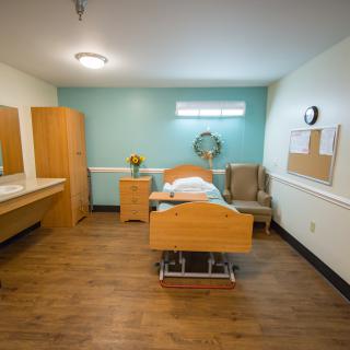 A clean and organized hospital room with a bed, furniture, and medical equipment.