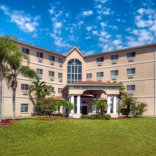 A hotel building with a grand entrance, surrounded by palm trees and set against a blue sky.