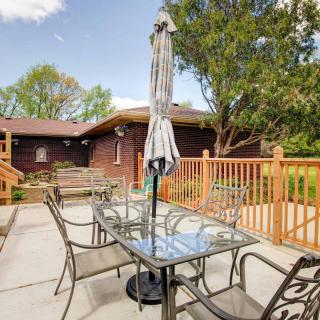 A patio area with a glass table, chairs, and an umbrella on a sunny day.