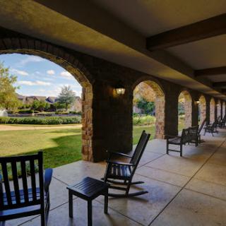 A serene outdoor porch with rocking chairs, offering a peaceful view of the landscaped garden.
