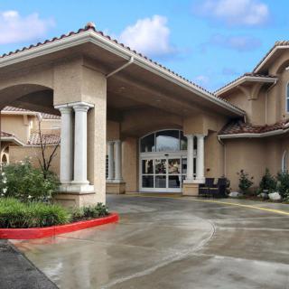 A residential building with a covered driveway entrance and columns.