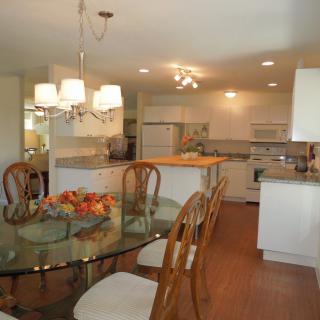A modern kitchen and dining area with wooden chairs and a glass table.