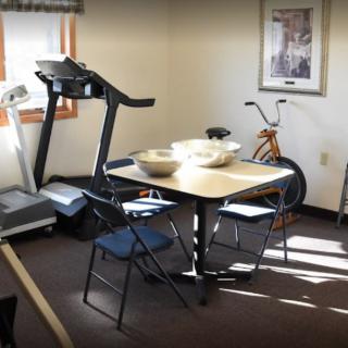A room with exercise equipment and a table with chairs.