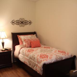 A cozy bedroom with a single bed, decorative pillows, and warm lighting.