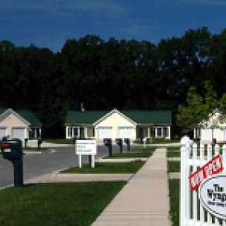 A suburban neighborhood with houses and a 'For Sale' sign.