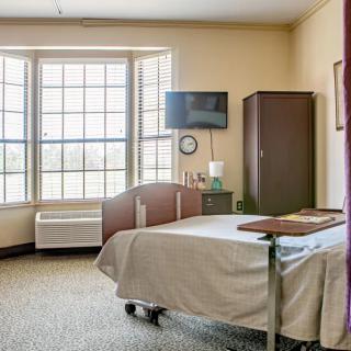 A hospital room with a single bed, large window, and minimal furnishings.