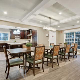 A spacious dining area with modern decor, featuring a large table and several chairs, adjacent to a well-equipped kitchen.