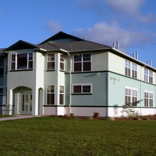 A two-story residential house with a well-maintained lawn and clear sky in the background.