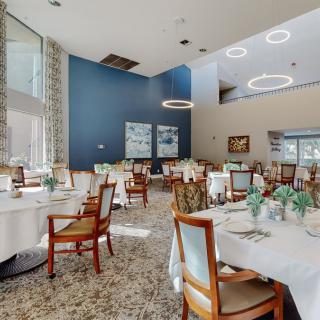 An elegant dining area with neatly arranged tables and chairs, featuring modern design elements and soft indoor lighting.
