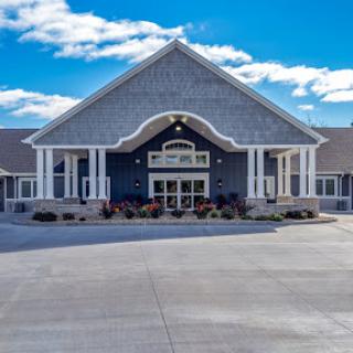 A modern building showcasing elegant architectural design, framed by a clear blue sky and fluffy clouds.