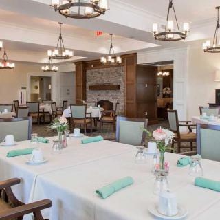 An elegantly set dining area with neatly arranged tables and chandeliers.