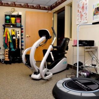 A physical therapy room equipped with a stationary exercise bike and various fitness tools to aid in rehabilitation.