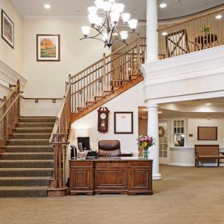 A welcoming hotel lobby with a grand staircase and elegant chandelier.