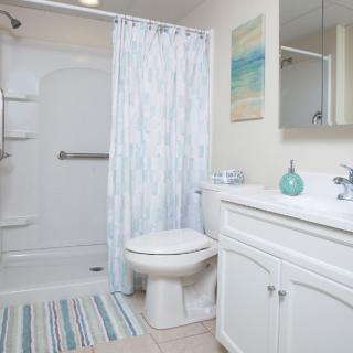 A modern and clean bathroom featuring a shower, toilet, and sink with minimalistic decor.