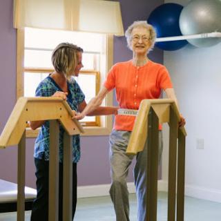 A healthcare professional assists a senior citizen during physical therapy, promoting mobility and independence.