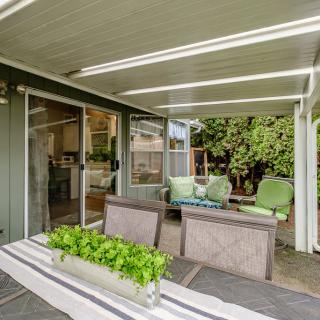 A cozy patio with comfortable outdoor seating under a covered area, surrounded by lush greenery.