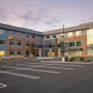 A modern commercial building with a spacious parking lot, showcasing contemporary architectural design.