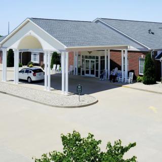 A building entrance with a covered driveway and parked car.