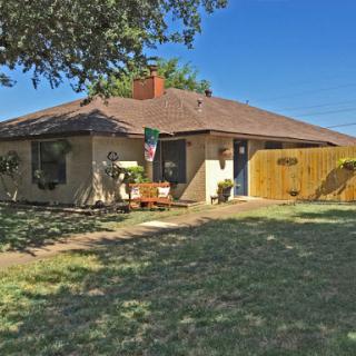Charming single-story home with a spacious yard and blue skies.