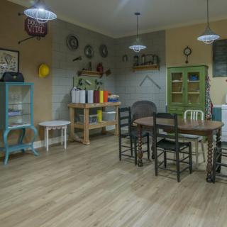 A cozy dining area with a mix of chairs around a wooden table, surrounded by shelves and decorative items.