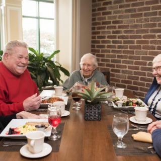 A group of seniors enjoying a meal together at a dining table.