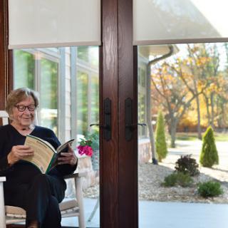 A person enjoying a peaceful moment reading indoors with a view of the autumn landscape outside.