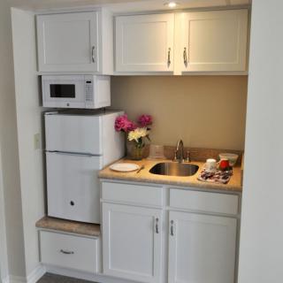 Compact mini kitchen setup with white cabinets and essential appliances.