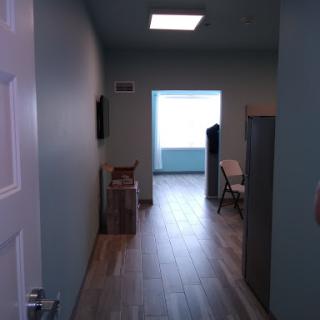 A view down a hallway in an office, showcasing a well-lit space with minimal furniture.