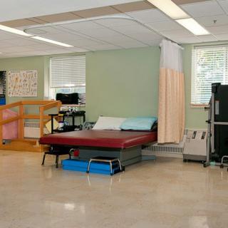 A physical therapy room equipped with exercise equipment and treatment tables.