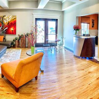A modern living room with vibrant decor, featuring hardwood floors, colorful furniture, and large windows allowing natural light to fill the space.