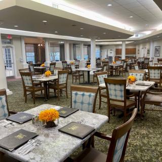 An elegant dining room with neatly set tables and floral decorations.