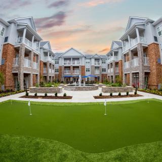 A modern apartment complex with a landscaped courtyard at sunset.