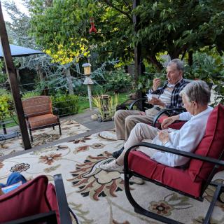 A family relaxing on a patio surrounded by lush greenery and comfortable seating.