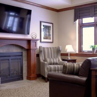A cozy living room with a fireplace, armchair, and television.
