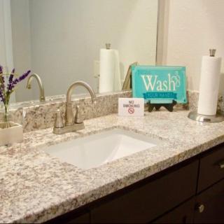 A bathroom countertop with a sink, faucet, and decorative items.