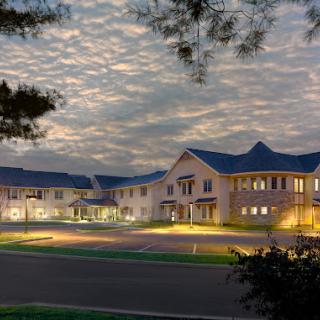 A beautifully lit residential building at dusk, surrounded by an evening sky filled with clouds.