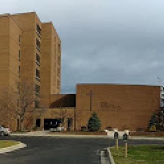 A view of a multi-story brick hospital building under a cloudy sky.