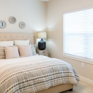 A serene and modern bedroom featuring soft tones, a plush bed, and natural light.