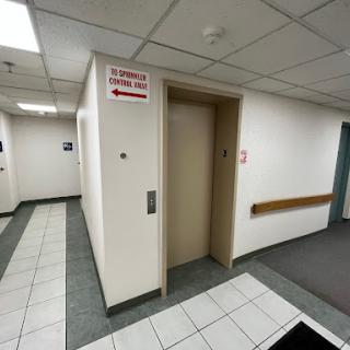 A hallway featuring an elevator and directional signage.