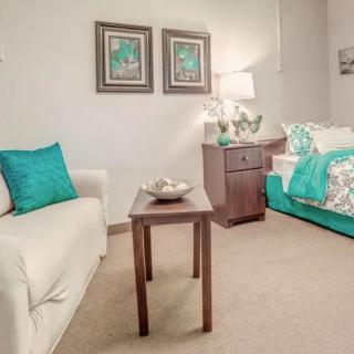 A cozy living room with a white sofa, teal accents, and a wooden side table.
