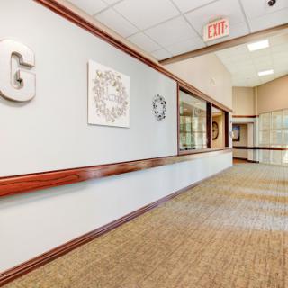 A clean and well-lit office hallway featuring decorative elements and a comfortable carpet.