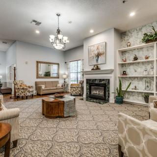 A cozy and elegantly decorated living room featuring a fireplace, comfortable seating, and a chandelier.
