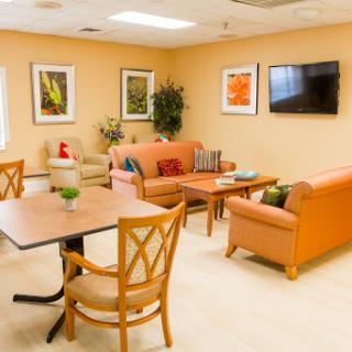A cozy lounge area with comfortable seating, vibrant artwork on the walls, and a television.
