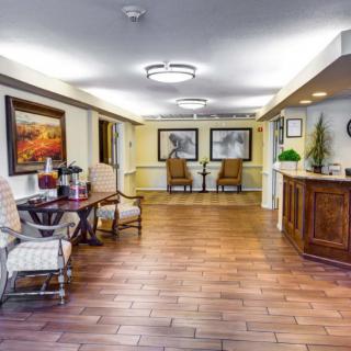 A well-lit lobby with wooden flooring, furnished with chairs and decorated with artwork.