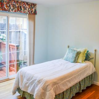 A cozy bedroom with a single bed and a sliding glass door allowing natural light to fill the room.