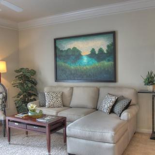 A cozy living room with a large painting above a comfortable sofa, complemented by a coffee table and decorative lighting.