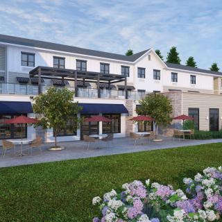 A modern hotel building with outdoor seating and landscaped gardens.